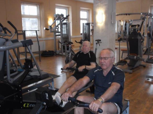 Två herrar sitter i roddmaskinen på gymmet och tränar tillsammans i Enköping